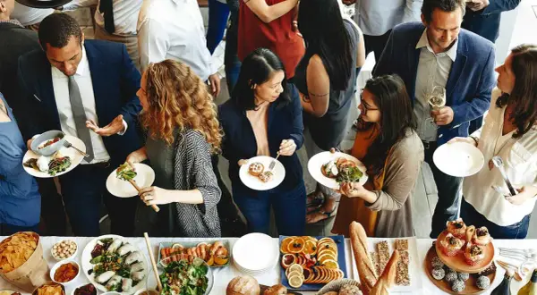 Gente disfrutando de la comida de personal en restaurantes, con una mesa llena de ensaladas, mariscos, frutas y pan.