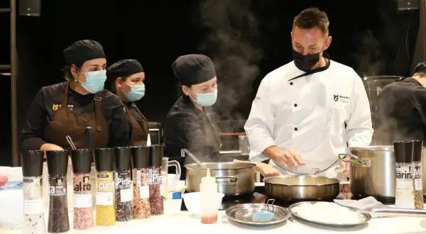 Un chef ejecutivo supervisa a su equipo en la cocina, rodeado de vapor y condimentos.