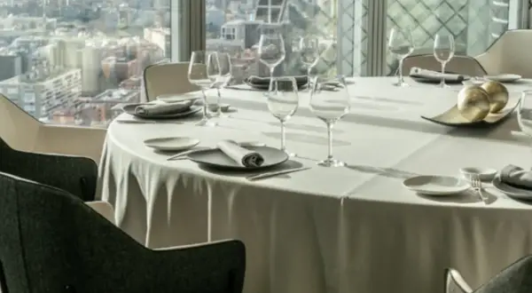 Mesa elegante en un restaurante con vistas a la ciudad, ideal para disfrutar de los mejores restaurantes de España.