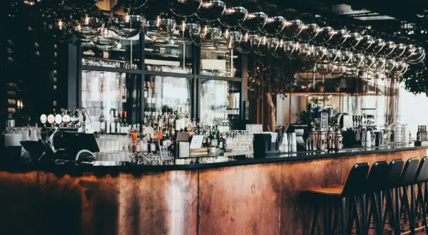 Barra de cobre pulido, botellas de licor, vasos y taburetes en este moderno bistro.