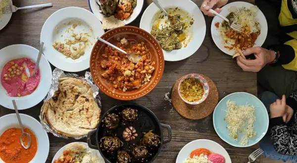 Mesa llena de platos variados, perfectos para recetas de cenas con amigos. Hummus, garbanzos, alcachofas y pan pita.