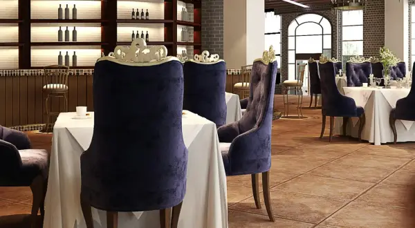 Elegantes sillas de terciopelo púrpura y mesas vestidas esperan a los comensales en este restaurante. El ambiente evoca nombres de restaurantes elegantes.