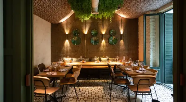 Elegante diseño de iluminación en restaurantes, con mesas puestas y vegetación colgante.