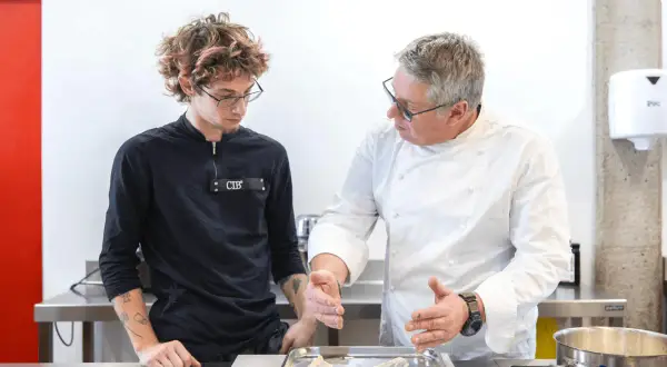 Un chef experimentado enseña a un joven aprendiz, mostrando diferentes tipos de chef en acción en una cocina profesional.