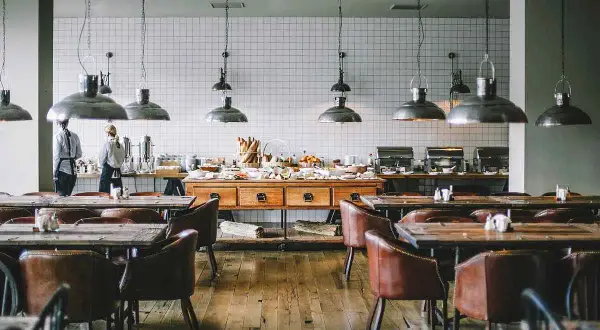 Mesas y sillas de cuero en un restaurante con un buffet. Se aprecian varias partes de un restaurante, como la zona de servicio y el comedor.