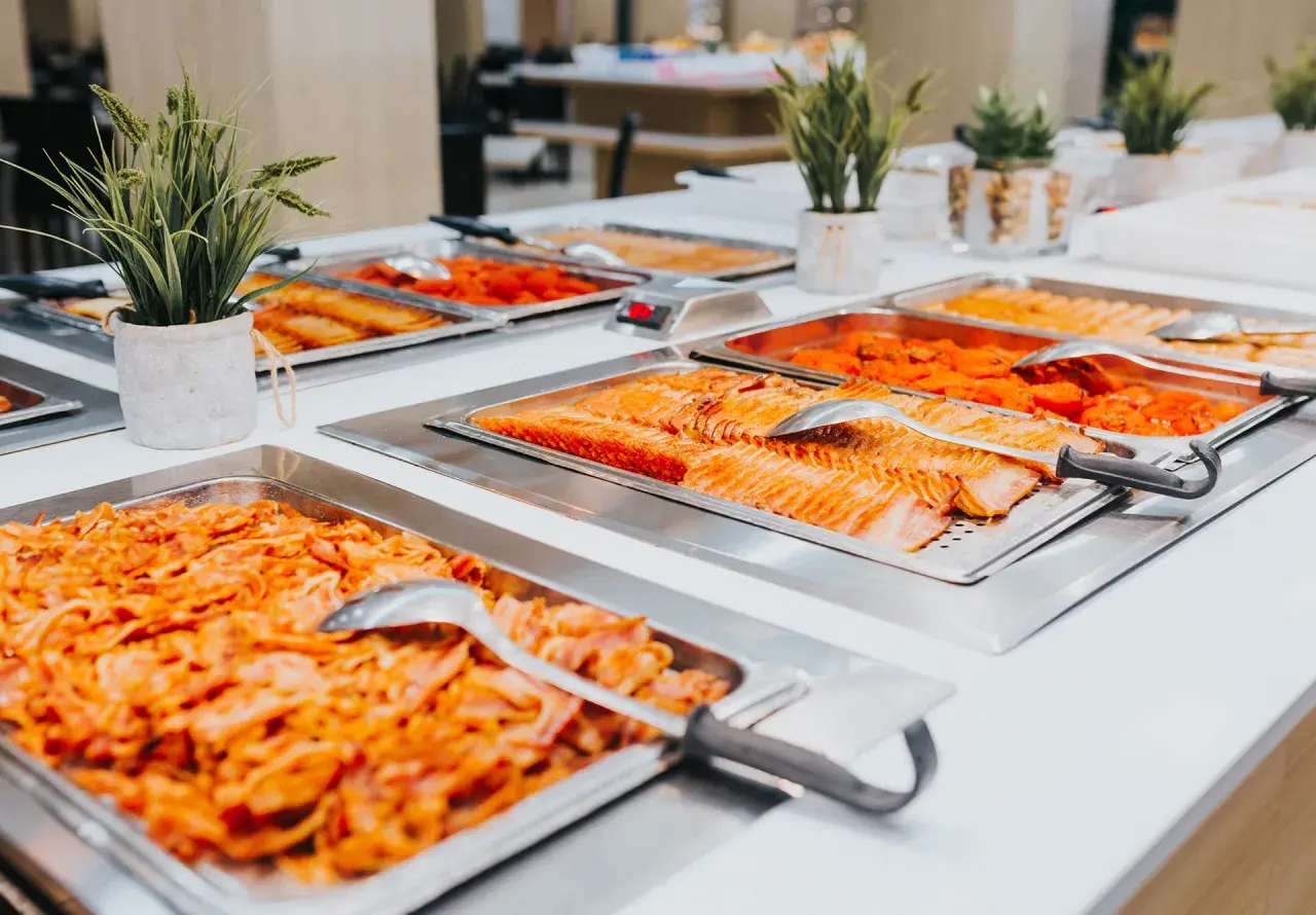 Bandejas de salmón y otros platos de quinta gama en un buffet.