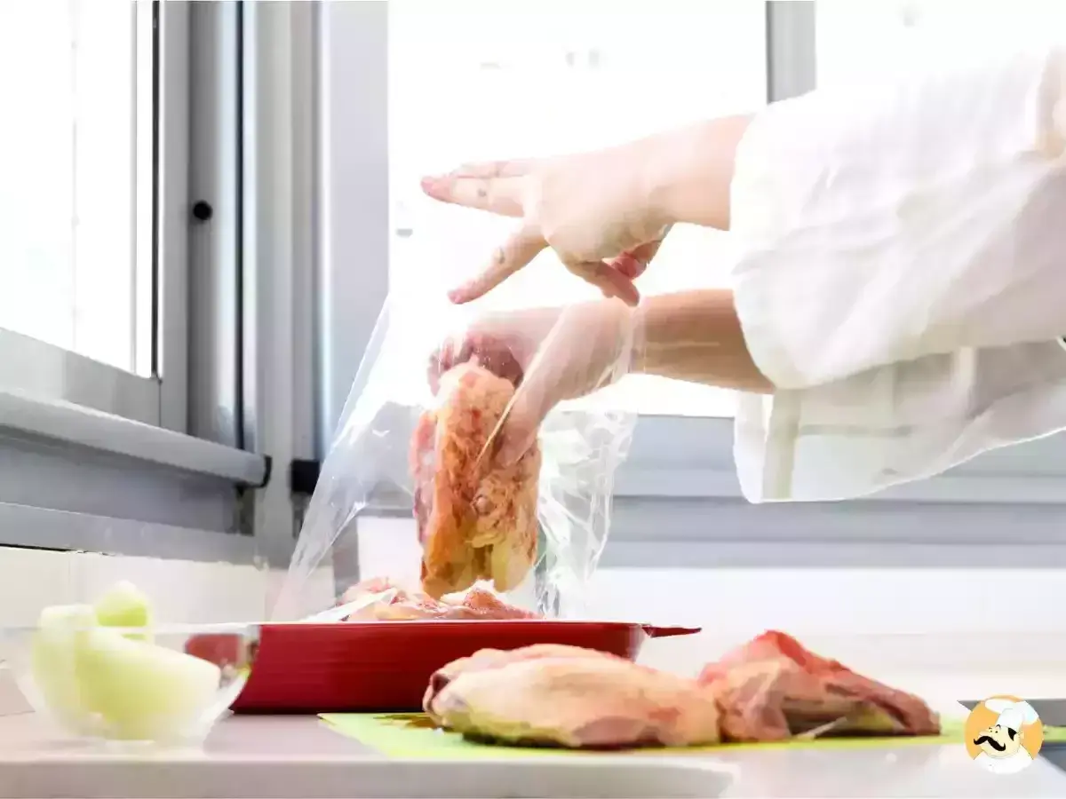 Manos con guantes introducen pollo en una bolsa para cocina al vacío.