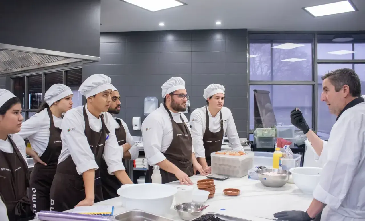 Chef instructor enseña a estudiantes a master food and beverage en una cocina profesional.