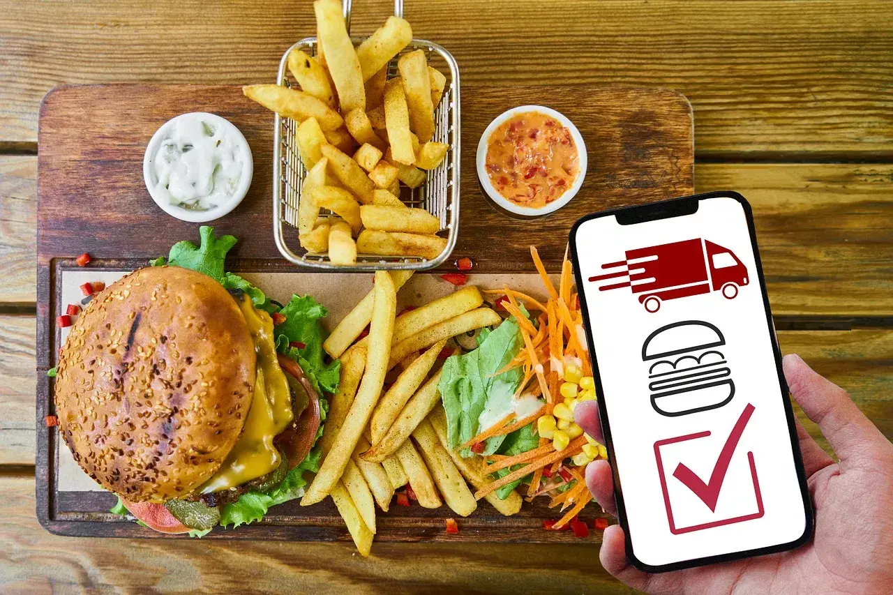 Hamburguesa, papas fritas y ensalada. El móvil muestra un camión de reparto y una hamburguesa, indicando que es rentable un negocio de comida para llevar.