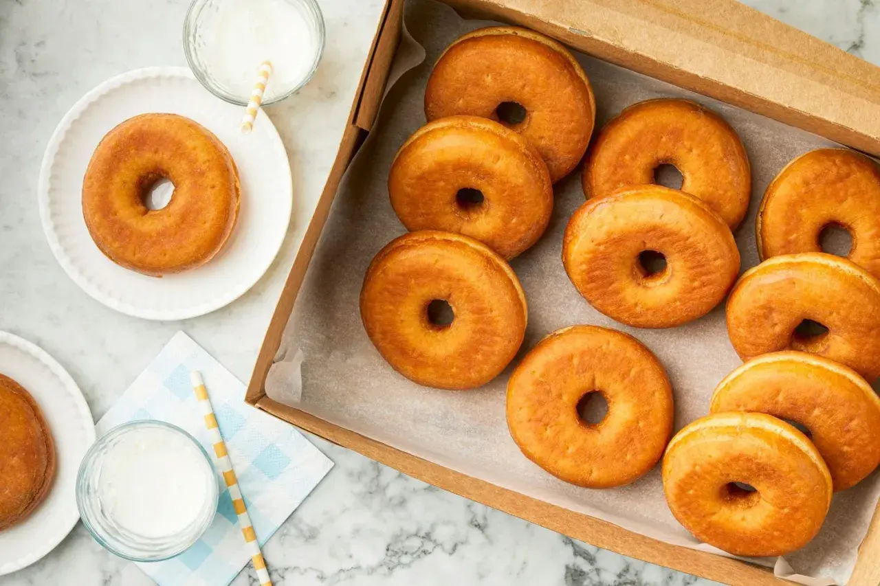 Una caja llena de deliciosos donuts dorados, perfectos para disfrutar o para saber que se pueden congelar los donuts y tenerlos listos para más tarde.