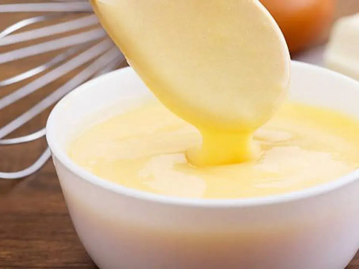 Crema pastelera cremosa cayendo de una cuchara a un bol. ¡Es bueno saber que se puede congelar la crema pastelera para usarla más tarde!