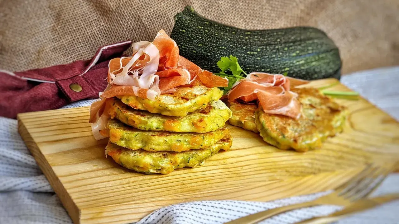 Deliciosas tortitas de calabacín apiladas y cubiertas con jamón serrano, listas para disfrutar.