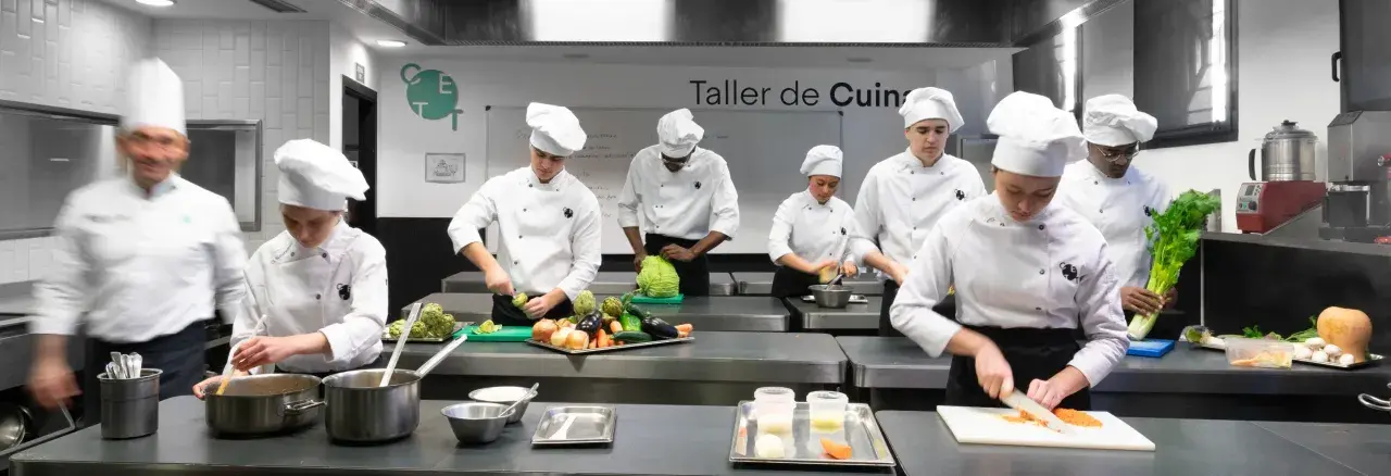 Estudiantes de un grado en ciencias gastronómicas practican cortes de verduras en un taller de cocina.