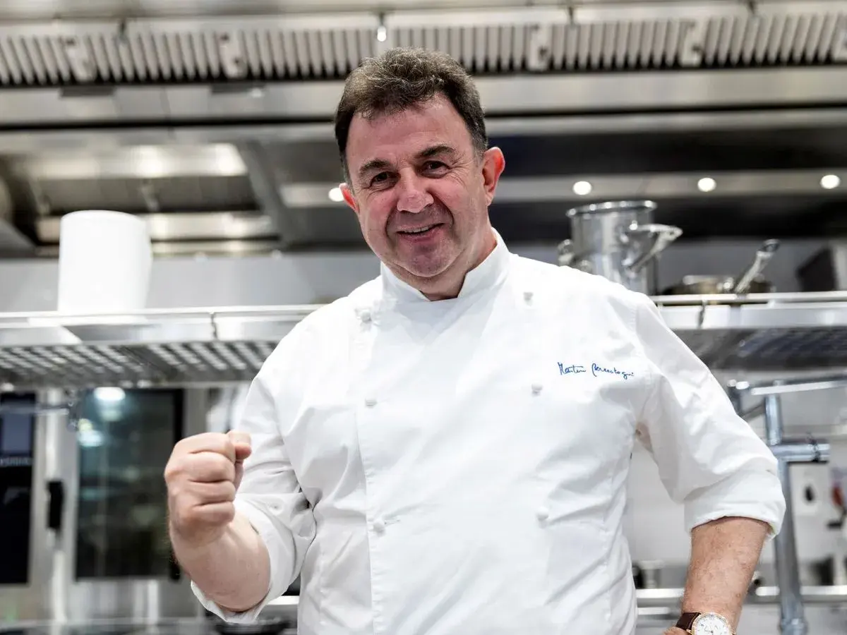 Chef Martín Berasategui, sonriendo y mostrando su puño, en su cocina. ¿Cuántas estrellas Michelin tiene Martín Berasategui?