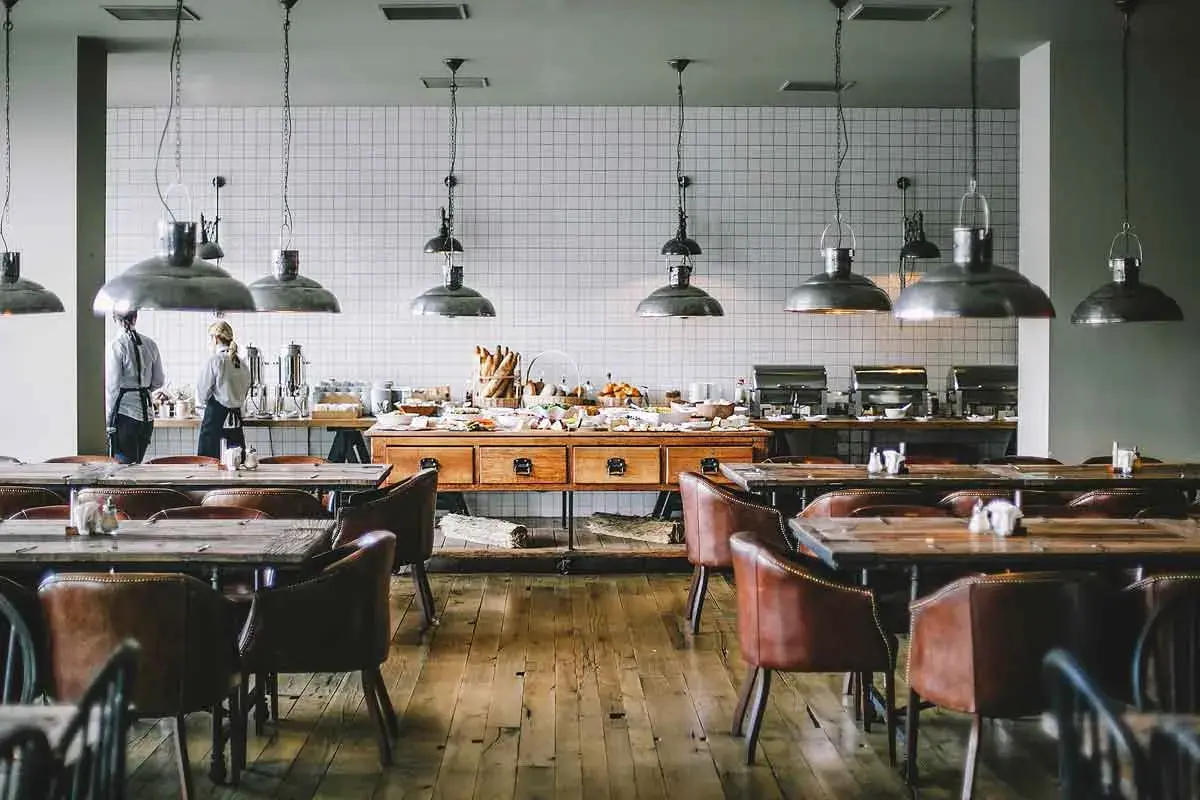 Mesas y sillas de cuero en un restaurante con un buffet. Se aprecian varias partes de un restaurante, como la zona de servicio y el comedor.