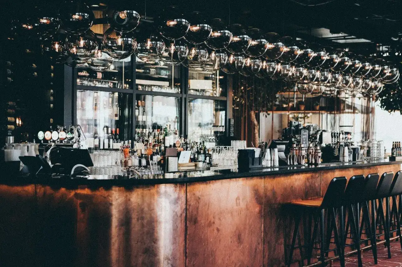 Barra de cobre pulido, botellas de licor, vasos y taburetes en este moderno bistro.