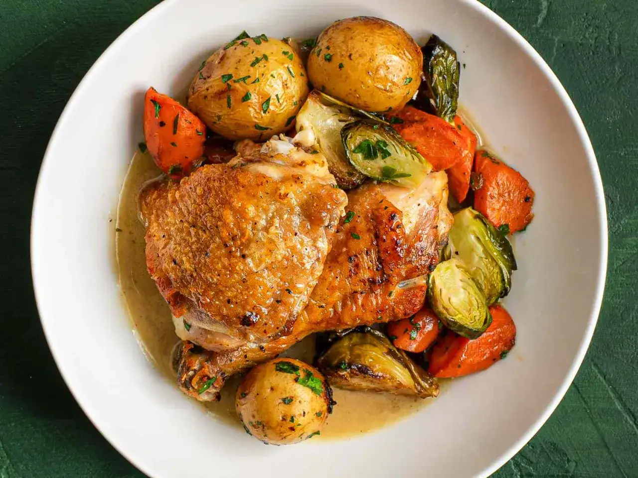 Pollo asado con patatas, zanahorias y coles de Bruselas. Un plato perfecto para tus recetas horno saludables.