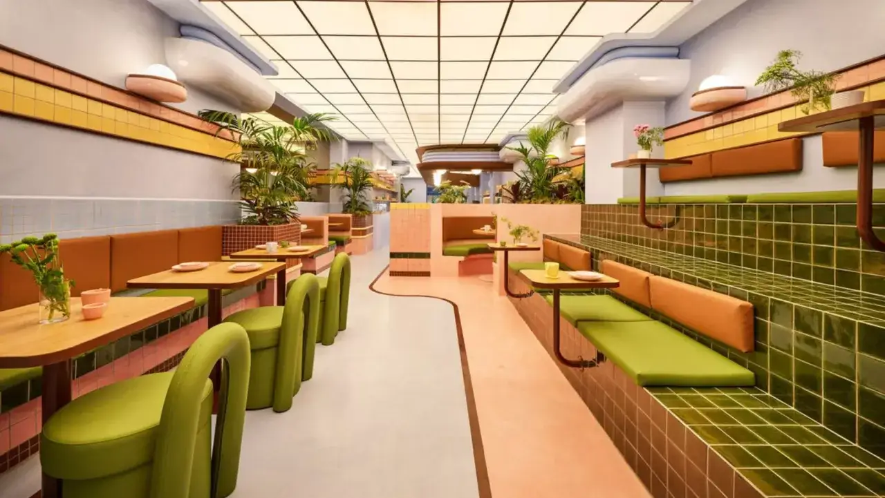 Un restaurante con diseño retro, donde la restauración se vive en cada detalle: asientos verdes, paredes rosas y plantas.