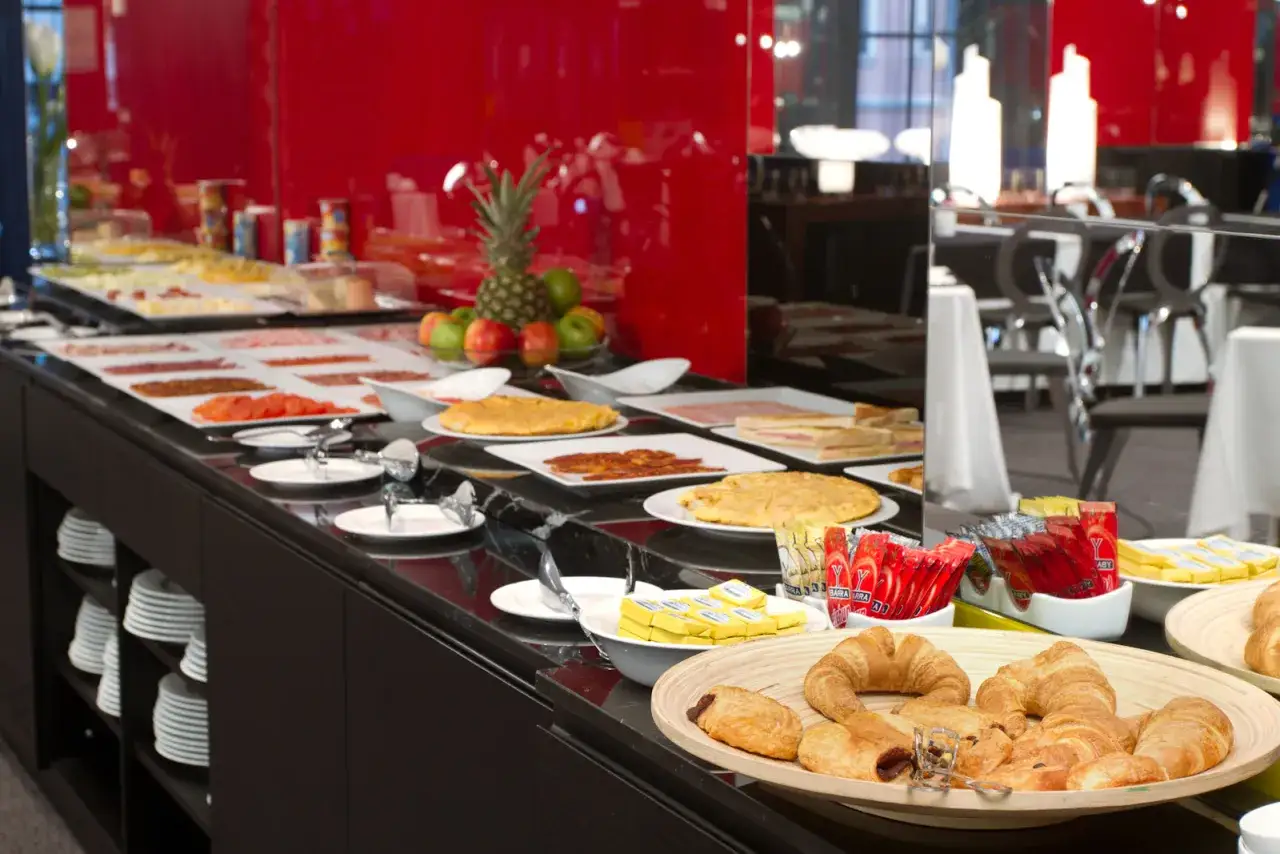 Un delicioso buffet de desayuno con tortillas, sándwiches, frutas y bollería.