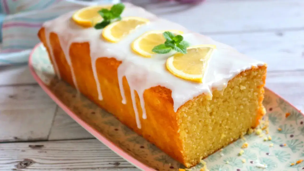 Un delicioso plumcake de lim&oacute;n cubierto con glaseado blanco y decorado con rodajas de lim&oacute;n y hojas de menta.