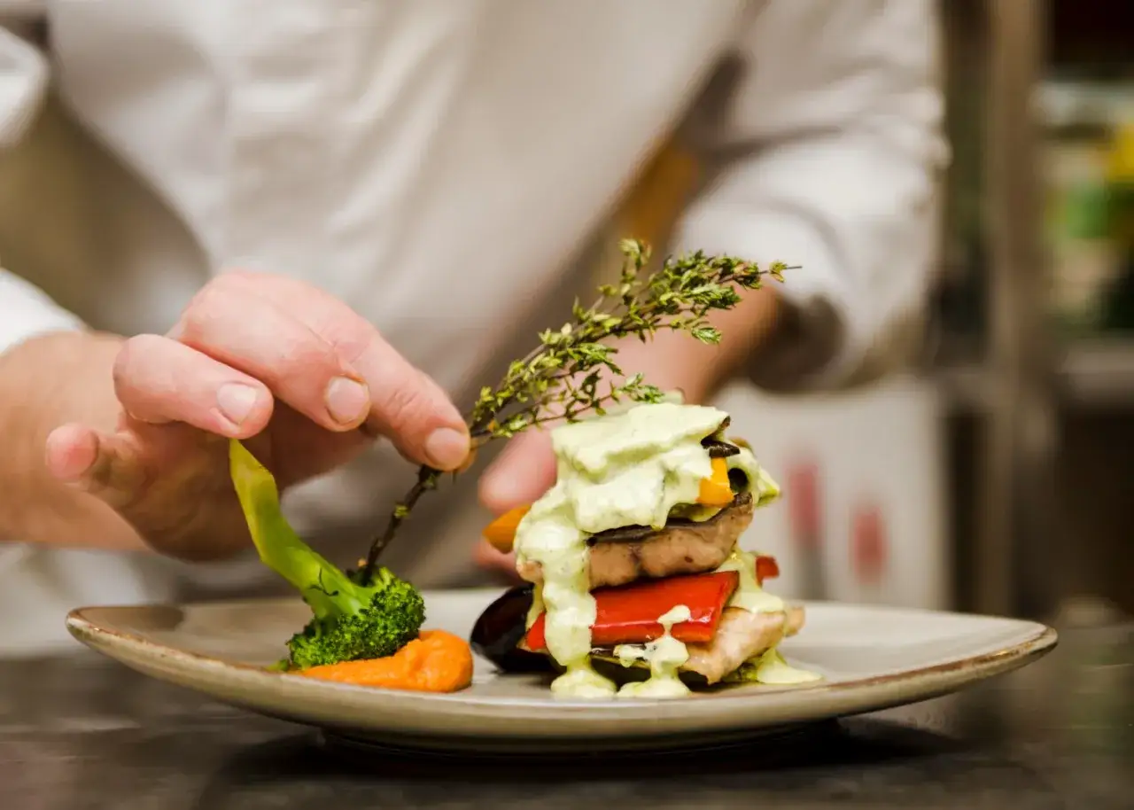 Chef decora un plato con br&oacute;coli y hierbas. Un paso m&aacute;s para aprender a cocinar.
