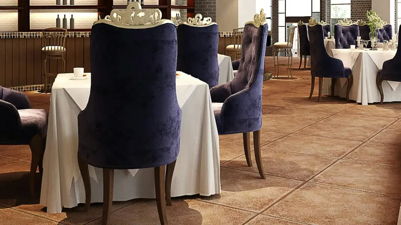 Mesas vestidas y sillas de terciopelo p&uacute;rpura, un ambiente que evoca nombres de restaurantes elegantes.