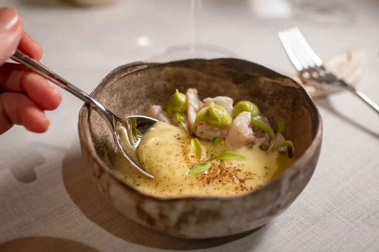 Un plato de gambas y aguacate con salsa cremosa, parte de un men&uacute; degustaci&oacute;n.