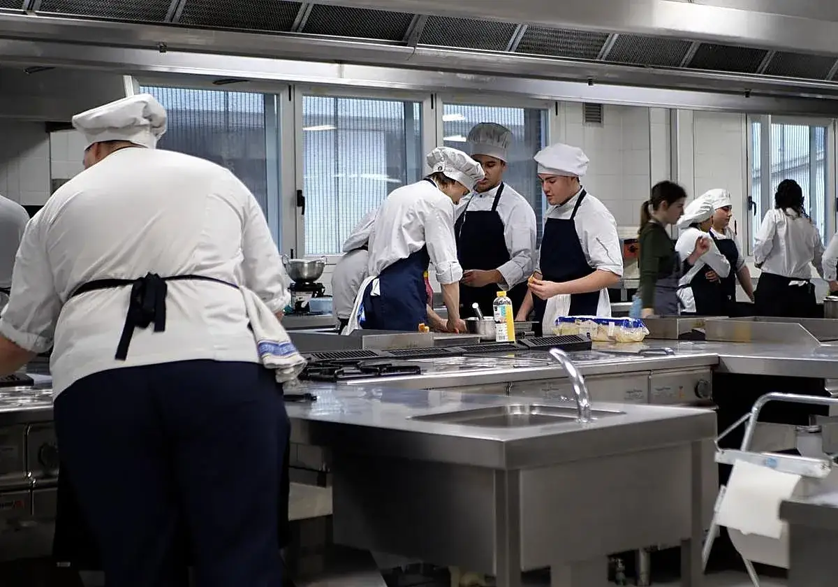 Estudiantes en cursos de chef aprenden en una cocina profesional.