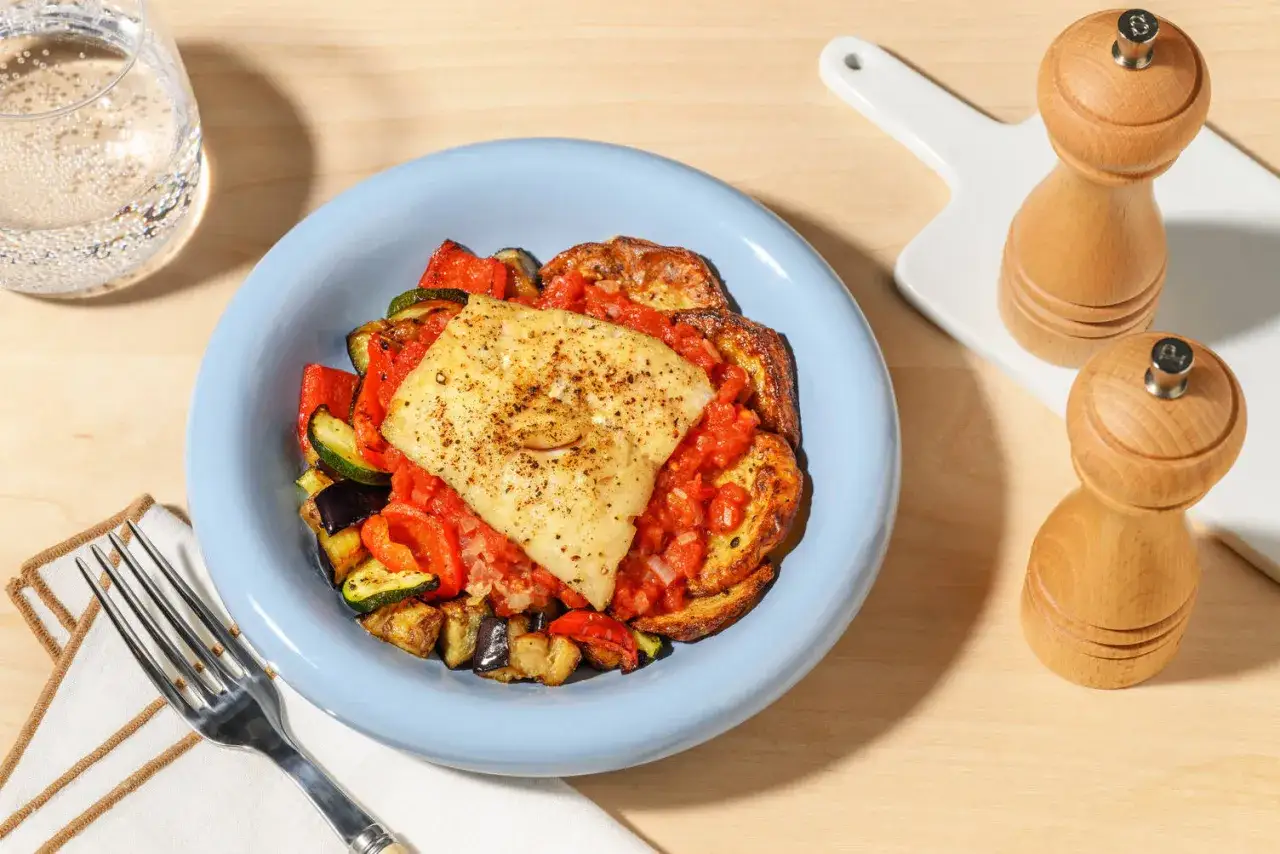 Filete de pescado con verduras asadas y salsa de tomate, una comida saludable que te encantar&aacute; si buscas un coach de nutrici&oacute;n.