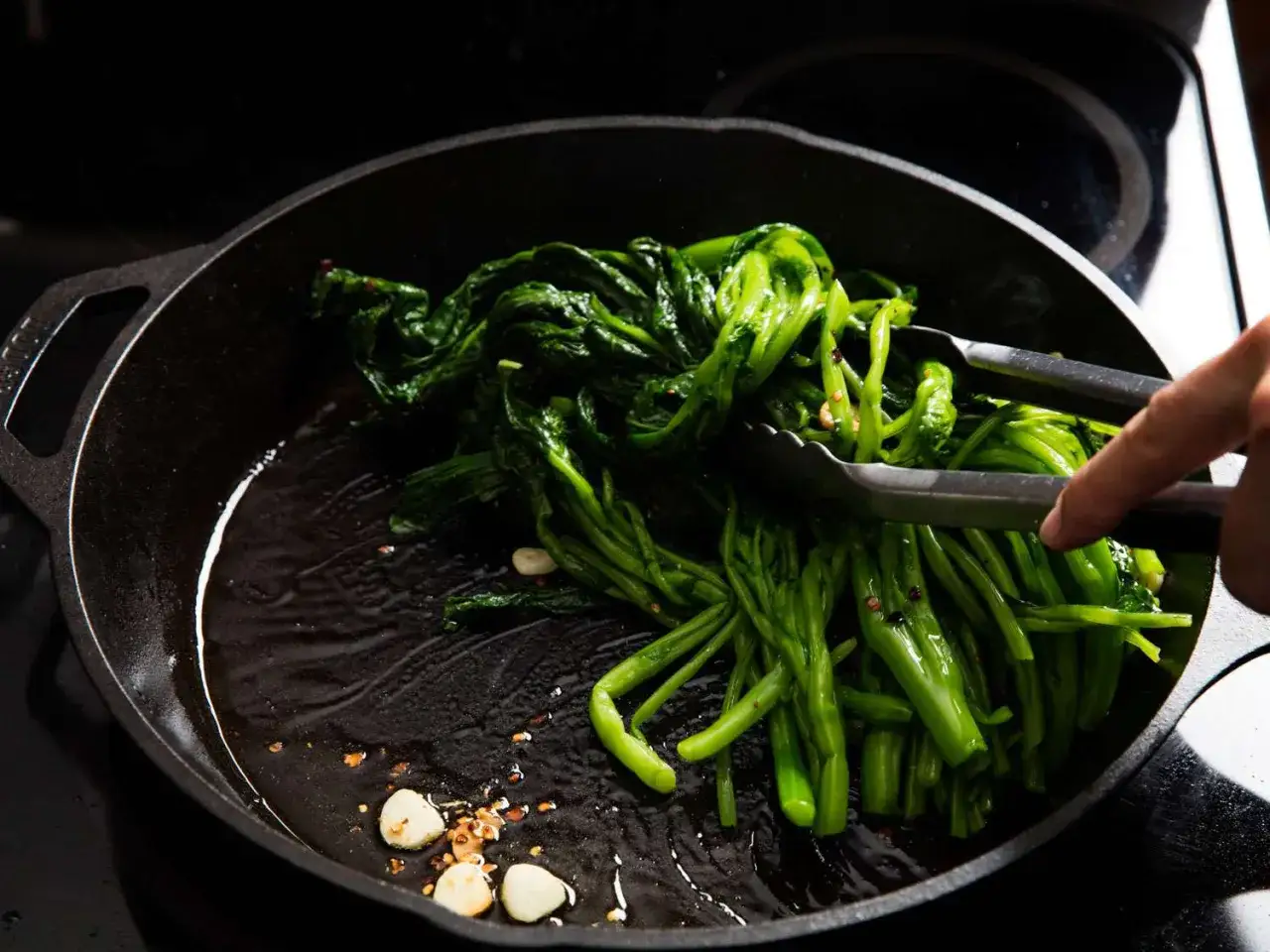 Verduras verdes se rehogan en sart&eacute;n de hierro fundido con ajo.