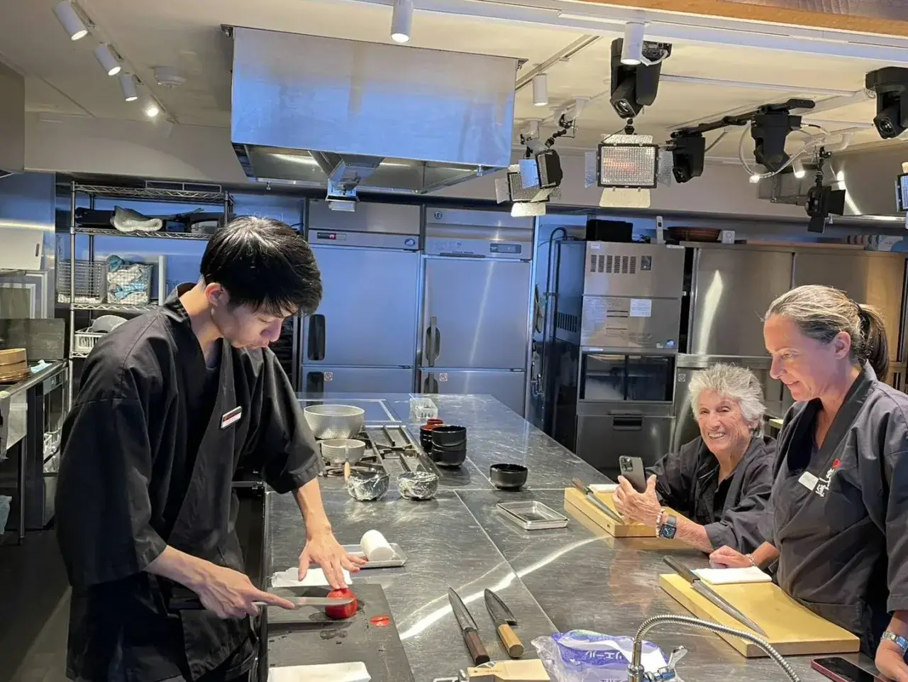 Chef ense&ntilde;a a dos mujeres a aprender a hacer sushi en una cocina profesional.