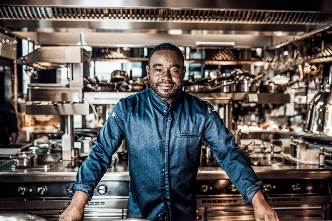 Chef con mas estrellas Michelin, sonriente en una cocina profesional, rodeado de equipos y utensilios.