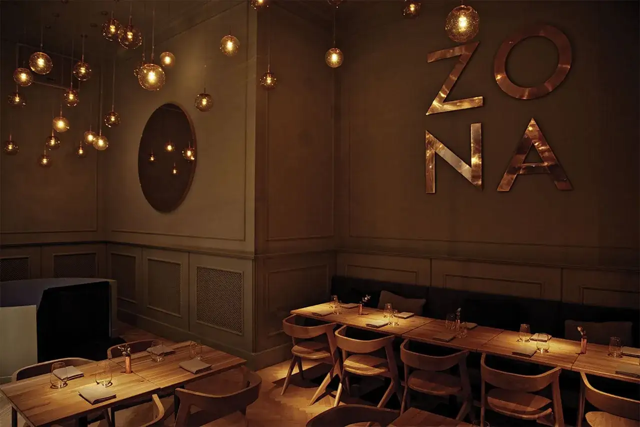 Elegante dise&ntilde;o de iluminaci&oacute;n para restaurantes, con l&aacute;mparas colgantes doradas y el letrero 