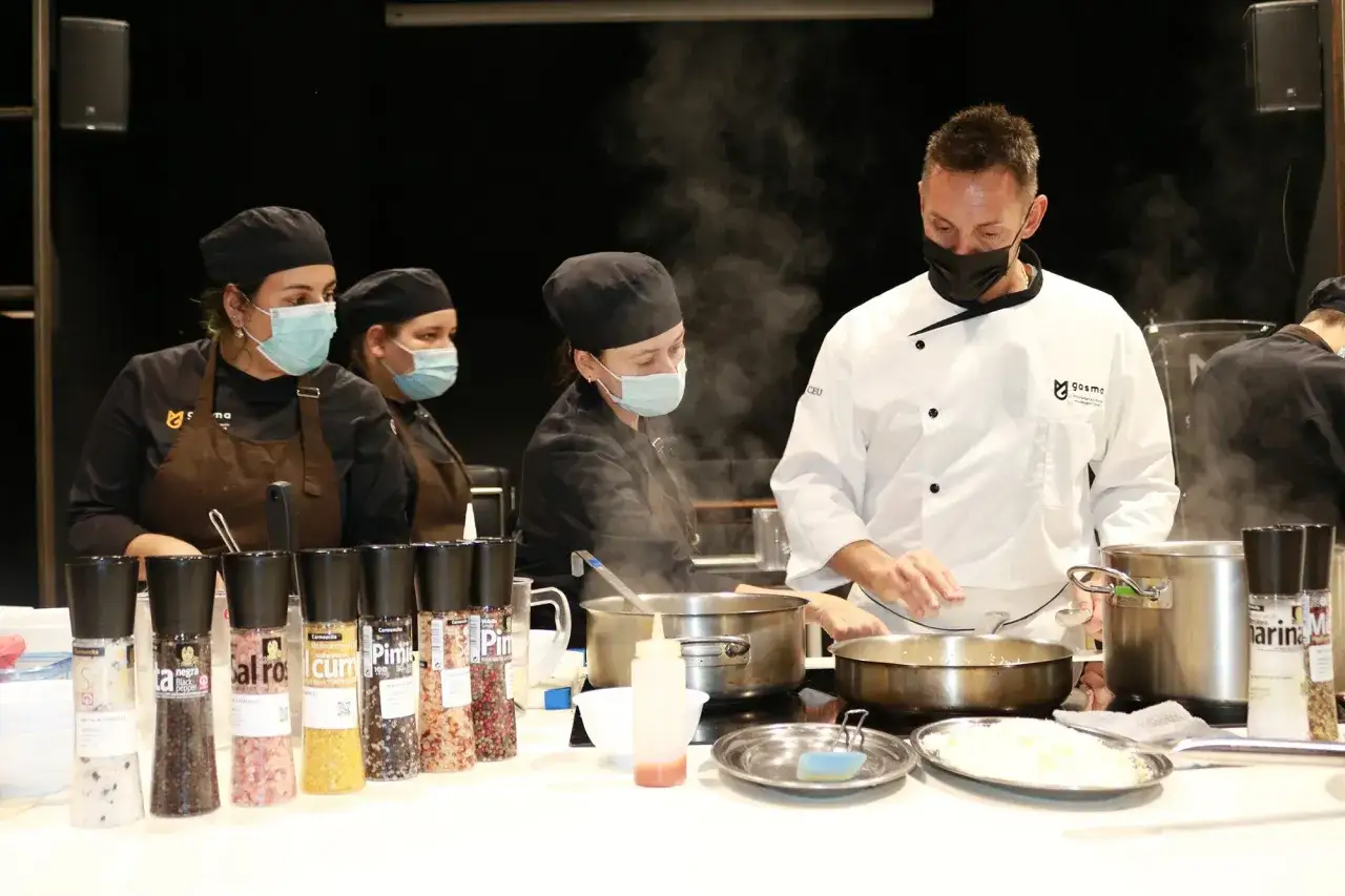 Un chef ejecutivo supervisa a su equipo en la cocina, rodeado de vapor y condimentos.