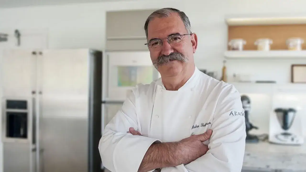Chef con bigote, con los brazos cruzados, en una cocina moderna. Un referente en la lista cocineros estrellas Michelin.