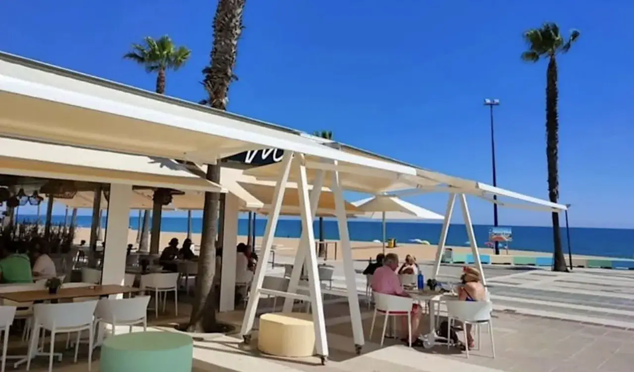 Terraza de restaurante en la playa, gente disfrutando del sol. ¿Buscas como conseguir un solete Repsol? Aquí seguro que lo encuentras.