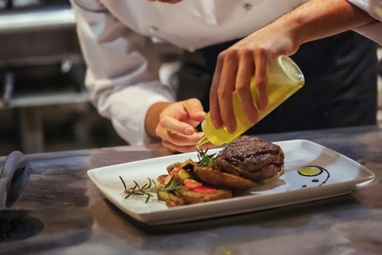 Un chef a&ntilde;ade aceite a un plato de carne y verduras. &iquest;Cu&aacute;nto gana un cocinero en Espa&ntilde;a?
