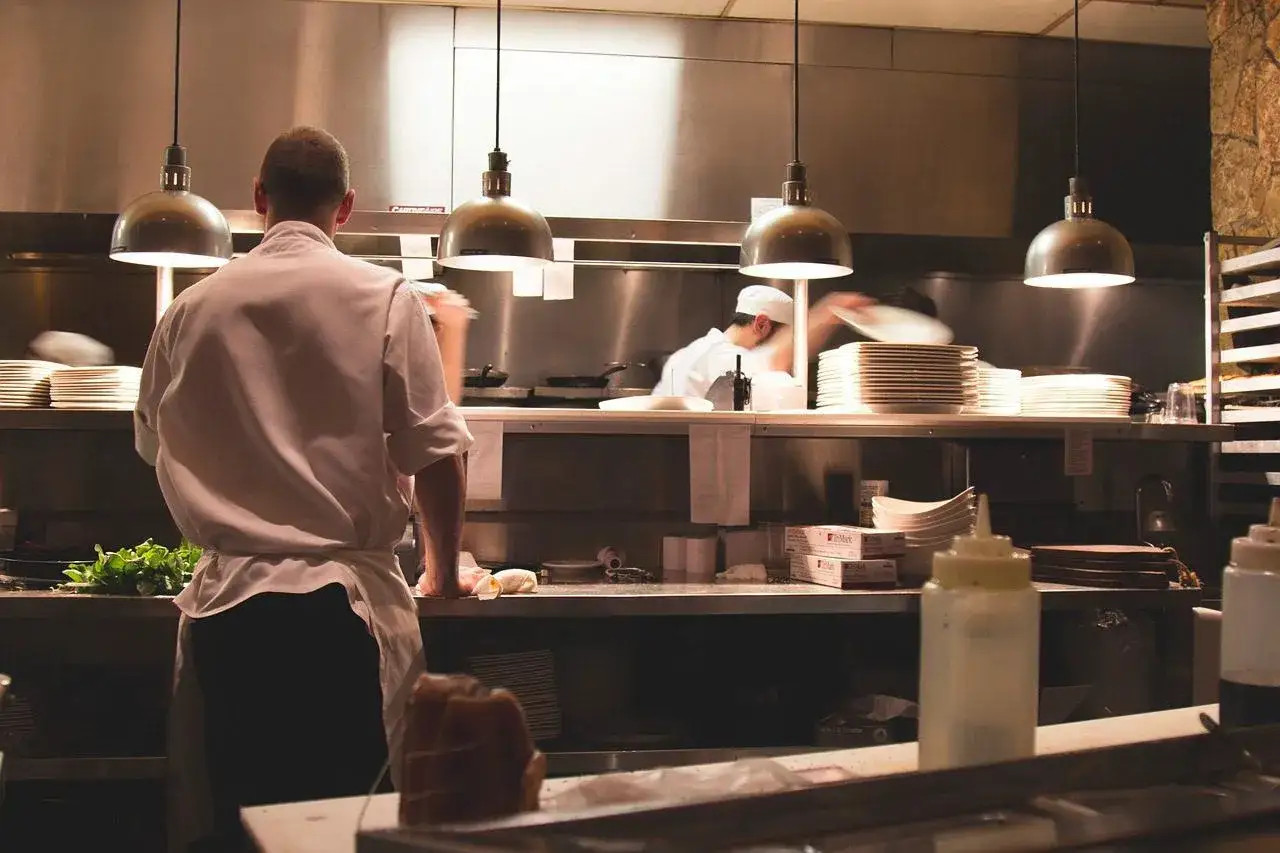 Chefs preparan platos en una cocina profesional, ideal para cursos de cocina saludable.