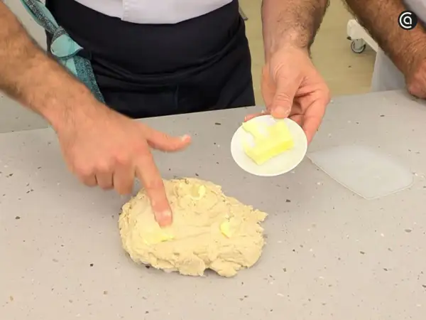Man integrando mantequilla a la masa, un paso clave en la autolisis para un pan perfecto.
