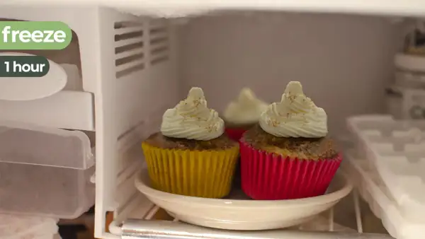Dos magdalenas con glaseado blanco y canela, en sus envoltorios amarillo y rosa, están en el congelador. ¡Las magdalenas se pueden congelar!