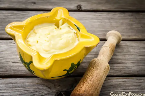 Alioli cremoso en mortero amarillo, listo para tu receta.