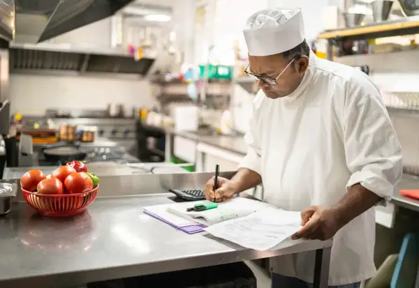 Chef calculando el coste de los ingredientes, un ejemplo de que es un escandallo en cocina.
