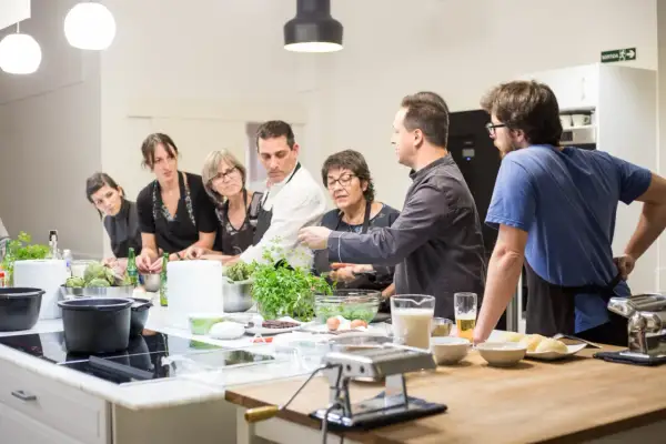 Grupo de personas aprendiendo en un curso de cocina mediterránea. Ingredientes frescos y utensilios listos para cocinar.