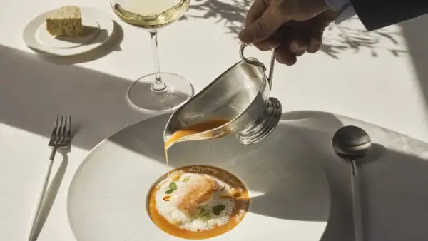 Servicio de sopa de marisco en un restaurante estrella Michelin. Un camarero vierte el caldo sobre un langostino y espuma.