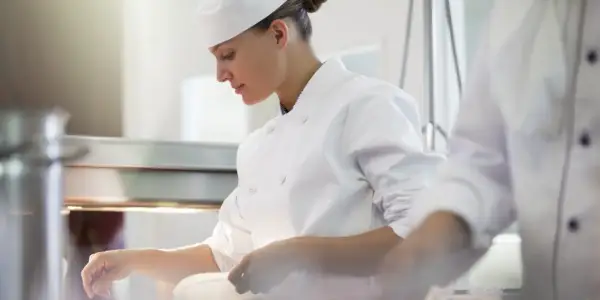 Chef concentrada en su labor, junto a otro chef en la cocina.