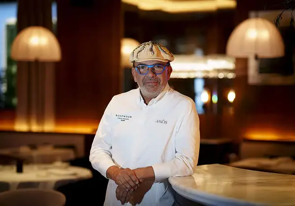 Un chef español con estrella Michelin, con gafas azules y gorra, posa en un elegante restaurante.