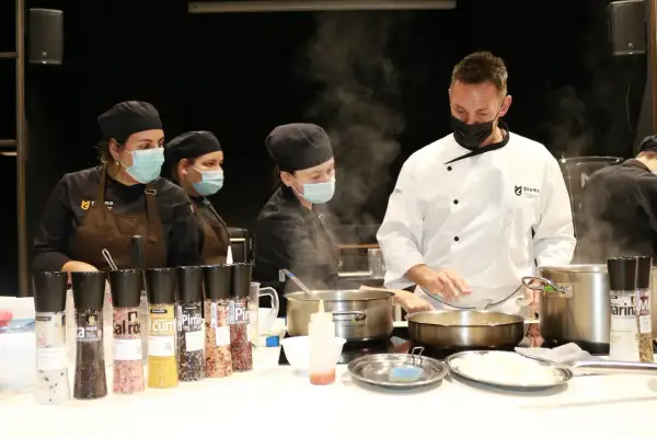 Un chef ejecutivo supervisa a su equipo en la cocina, rodeado de vapor y condimentos.