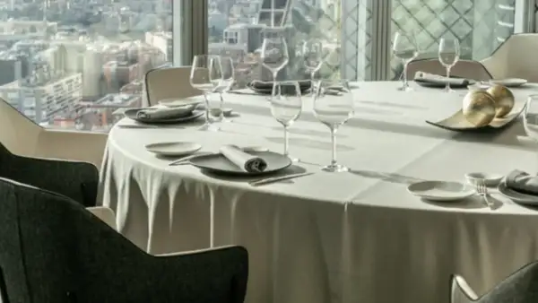 Mesa elegante en un restaurante con vistas a la ciudad, ideal para disfrutar de los mejores restaurantes de España.