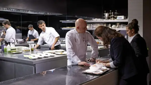 Chefs en cocina profesional preparan platos para conseguir una estrella Michelin.