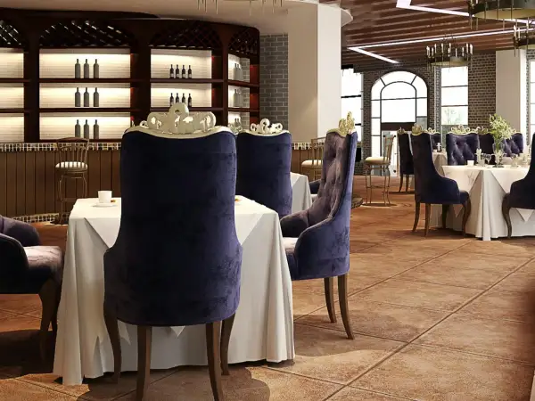Elegantes sillas de terciopelo púrpura y mesas vestidas esperan a los comensales en este restaurante. El ambiente evoca nombres de restaurantes elegantes.
